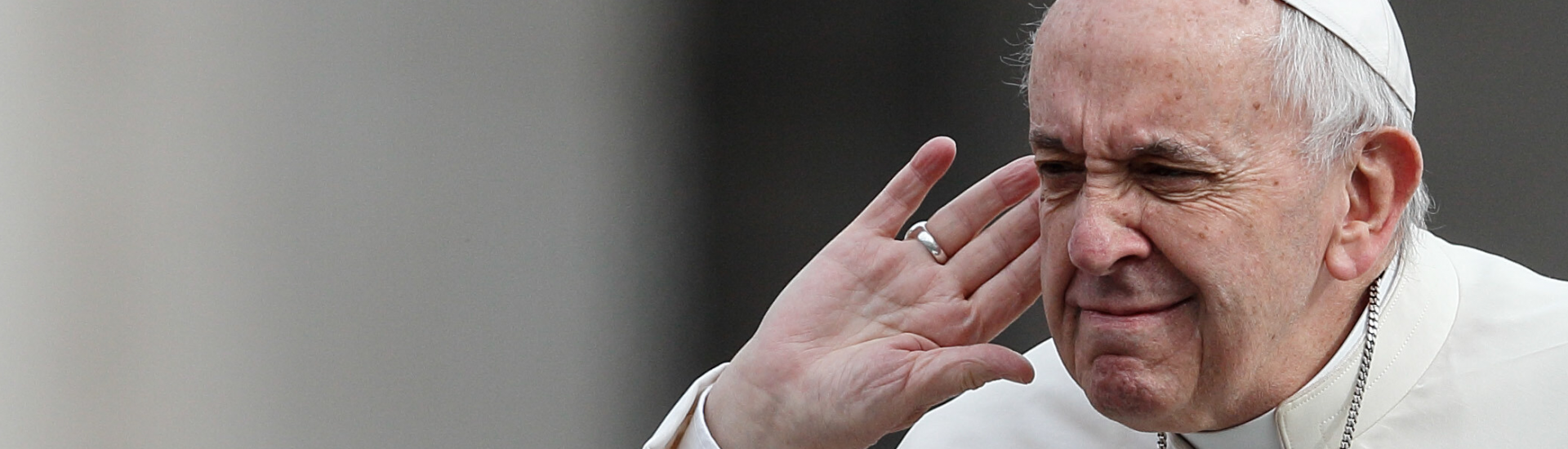 Der Papst hält die Hand ans Ohr und macht eine Geste des Hörens