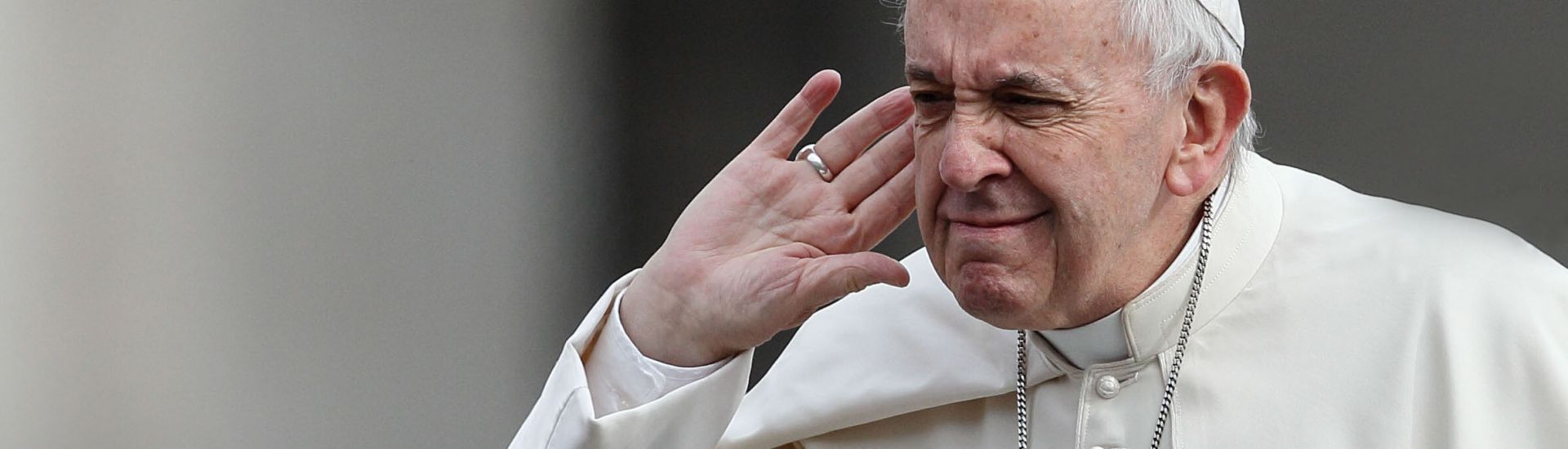 Papst Franziskus hält seine Hand ans Ohr, um zu hören.
